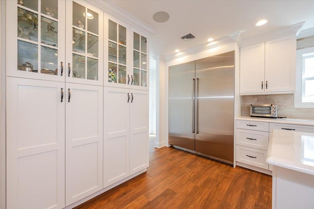 kitchen with dark wood-style floors, built in refrigerator, visible vents, white cabinetry, and light countertops