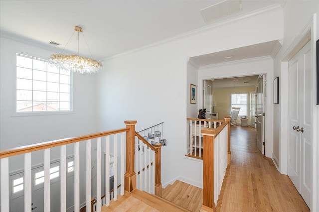 hall featuring light wood finished floors, an upstairs landing, visible vents, and an inviting chandelier