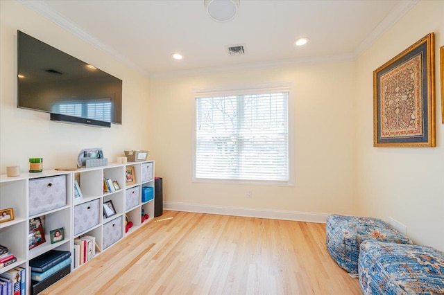 living area with a wealth of natural light, visible vents, wood finished floors, and crown molding
