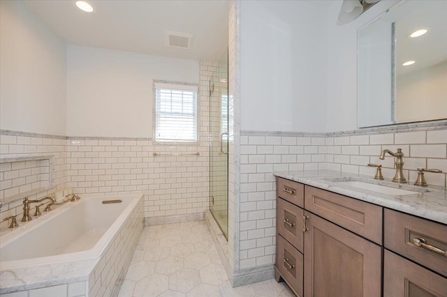 bathroom with visible vents, tile walls, a garden tub, vanity, and tile patterned flooring
