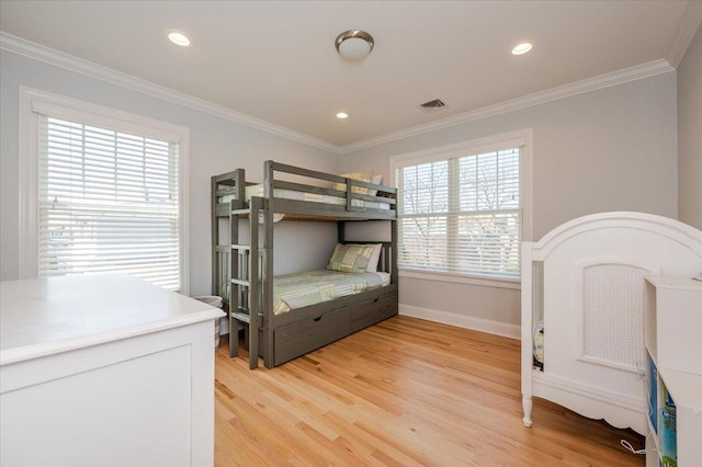 bedroom with baseboards, visible vents, ornamental molding, and light wood-type flooring