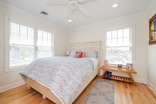 bedroom with baseboards, visible vents, crown molding, and light wood-style flooring