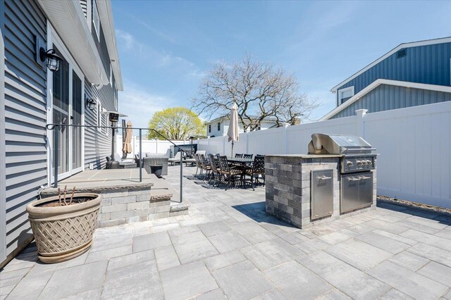 view of patio with outdoor dining space, an outdoor kitchen, a grill, and a fenced backyard