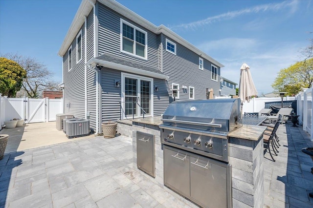 view of patio / terrace with a grill, a gate, a fenced backyard, and exterior kitchen