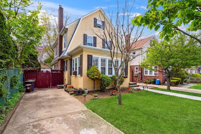 dutch colonial with fence, a front lawn, a gate, and stucco siding