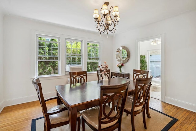 dining area with baseboards, an inviting chandelier, and light wood-style floors