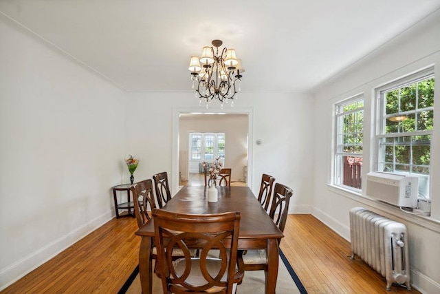 dining area with baseboards, light wood-style flooring, radiator heating unit, and a chandelier