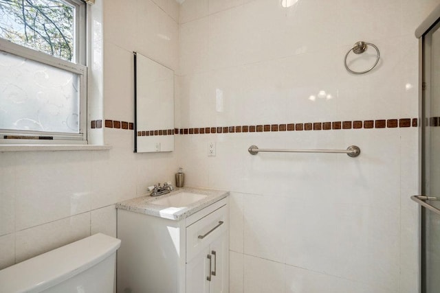 bathroom with vanity, toilet, and tile walls