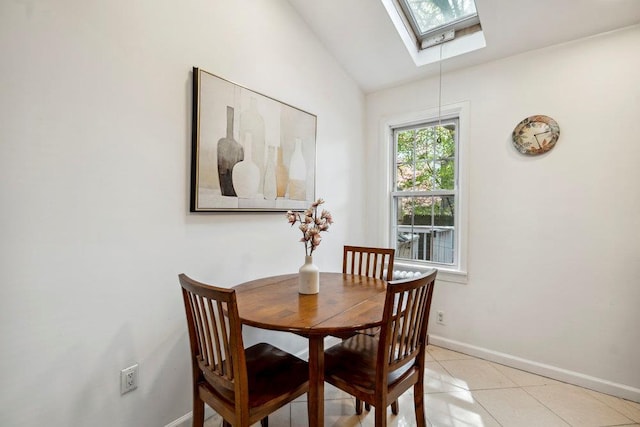 dining space with baseboards, light tile patterned floors, and lofted ceiling with skylight