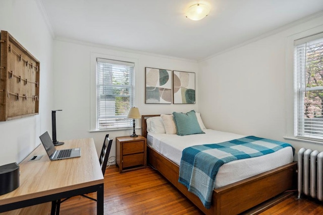 bedroom featuring multiple windows, radiator heating unit, and hardwood / wood-style floors