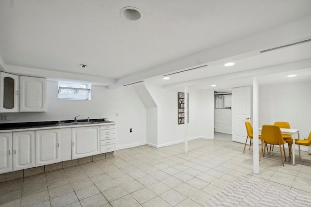 basement with recessed lighting, a sink, baseboards, and light tile patterned floors