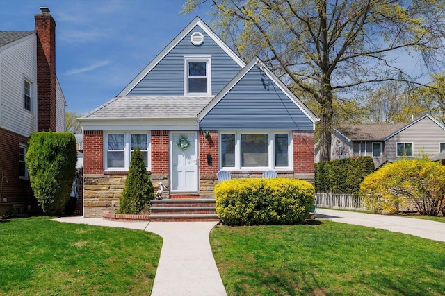 bungalow-style house with fence, a shingled roof, a front lawn, entry steps, and brick siding