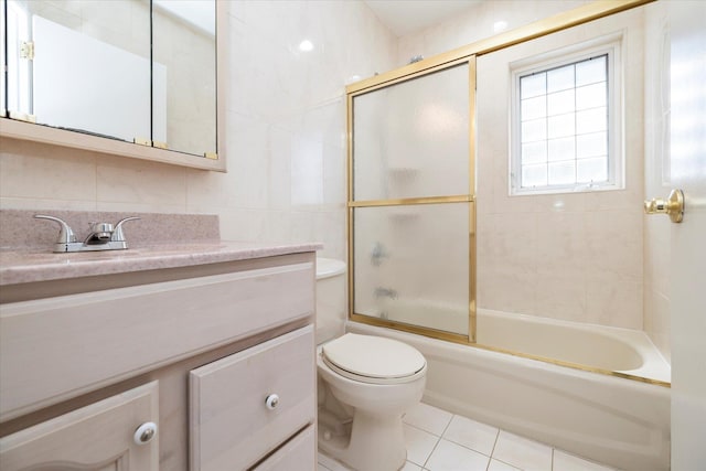 bathroom featuring tile patterned floors, shower / bath combination with glass door, toilet, tile walls, and vanity