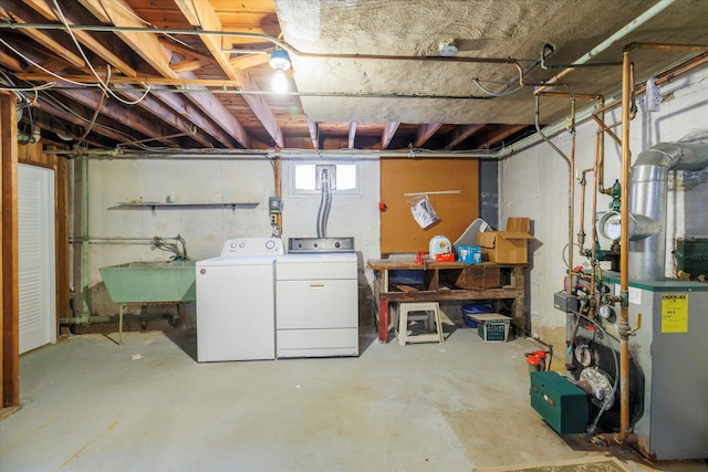 basement with washing machine and clothes dryer, a heating unit, and a sink