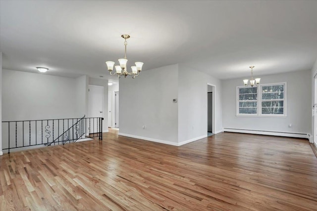 unfurnished room with a notable chandelier, a baseboard radiator, wood finished floors, and baseboards