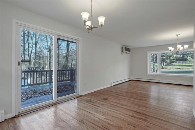 unfurnished dining area with wood finished floors, a wall mounted AC, a chandelier, and plenty of natural light