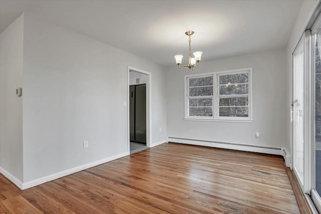 unfurnished room with an inviting chandelier, a baseboard radiator, wood finished floors, and baseboards