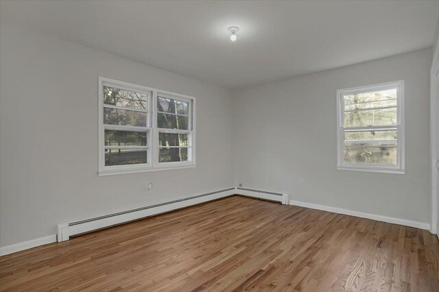 spare room featuring baseboards, baseboard heating, and wood finished floors