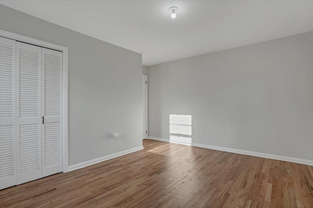 unfurnished bedroom with wood finished floors, a closet, and baseboards