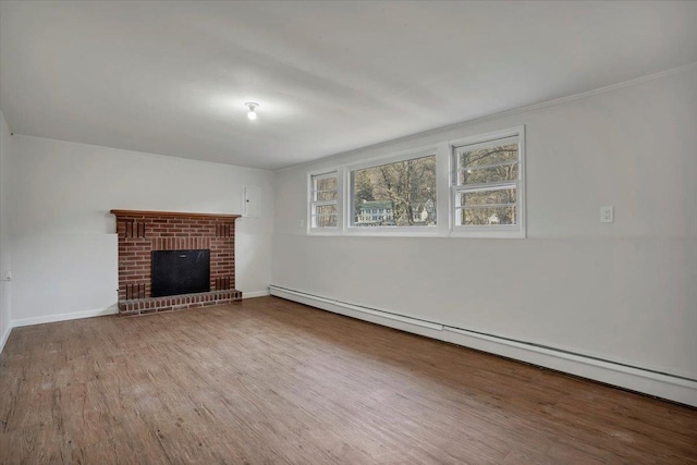 unfurnished living room featuring a brick fireplace, baseboard heating, wood finished floors, and baseboards