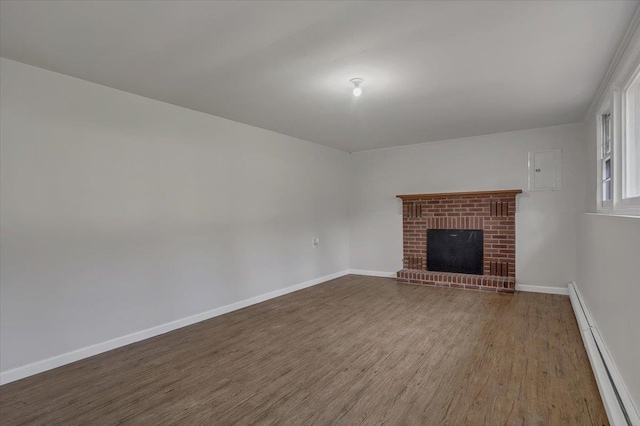 unfurnished living room featuring a fireplace, baseboard heating, wood finished floors, and baseboards