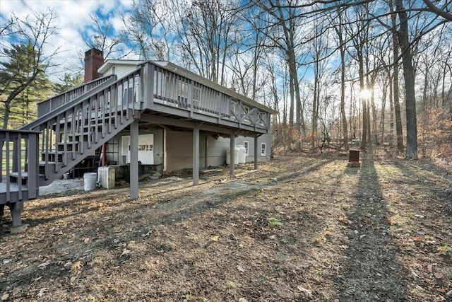 view of side of property featuring a deck, stairway, and a chimney