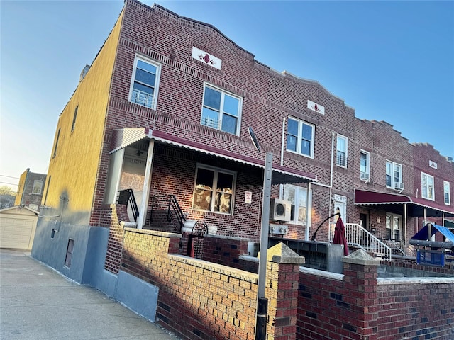 back of house featuring a fenced front yard, driveway, brick siding, ac unit, and a garage