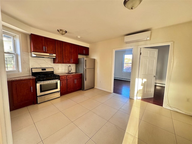 kitchen with under cabinet range hood, an AC wall unit, reddish brown cabinets, and stainless steel appliances