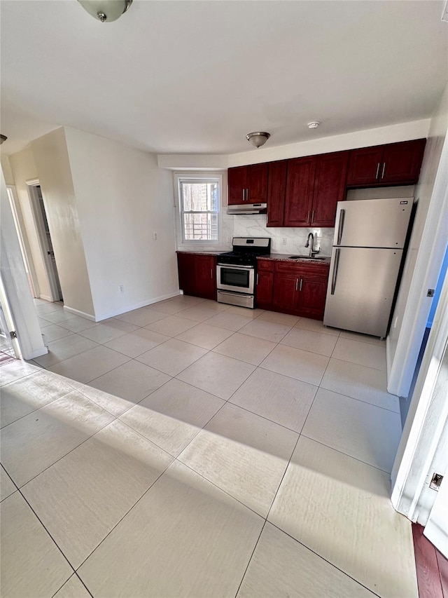kitchen featuring stainless steel range with gas stovetop, dark brown cabinets, freestanding refrigerator, backsplash, and under cabinet range hood