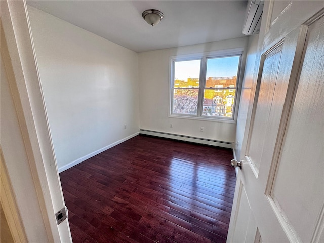 spare room featuring baseboard heating, hardwood / wood-style flooring, a wall unit AC, and baseboards