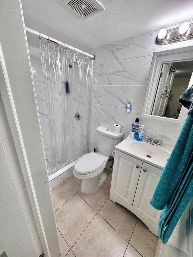 full bath featuring tile walls, visible vents, tile patterned floors, and a stall shower