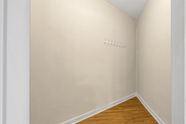 spare room with baseboards and wood finished floors