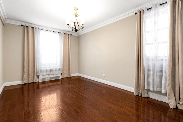 spare room featuring a chandelier, crown molding, baseboards, and hardwood / wood-style floors