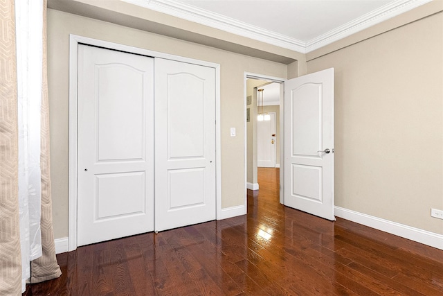 unfurnished bedroom featuring crown molding, baseboards, a closet, and wood finished floors