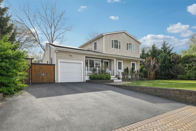 traditional-style house featuring a front yard, covered porch, a gate, driveway, and an attached garage