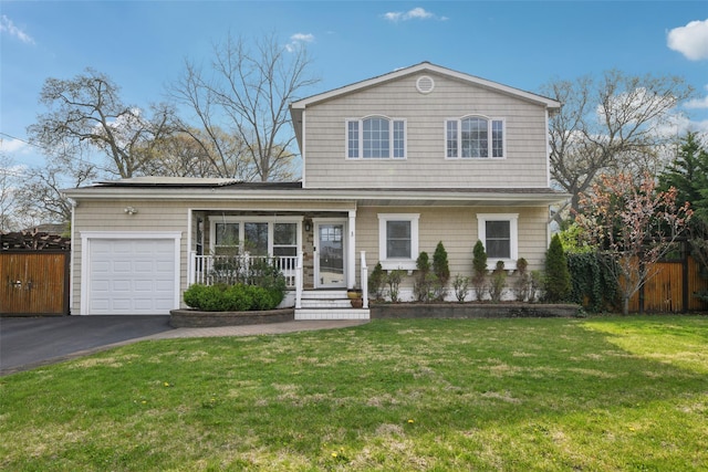 traditional-style house featuring driveway, fence, a porch, a front lawn, and a garage