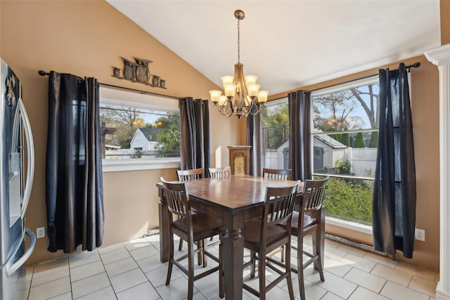 dining room featuring a healthy amount of sunlight, an inviting chandelier, light tile patterned flooring, and vaulted ceiling