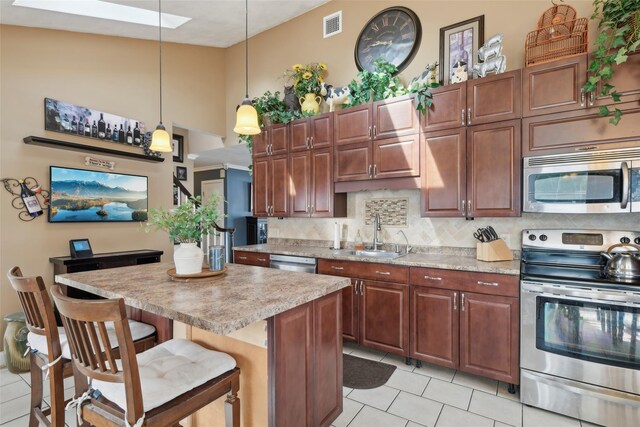 kitchen featuring appliances with stainless steel finishes, backsplash, a sink, visible vents, and light tile patterned flooring