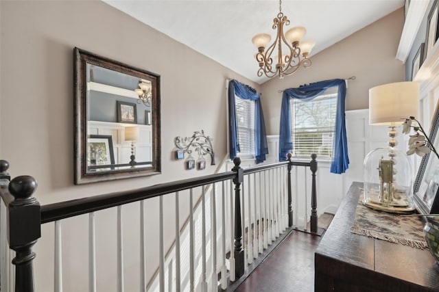 corridor featuring an upstairs landing, an inviting chandelier, and dark wood-style flooring