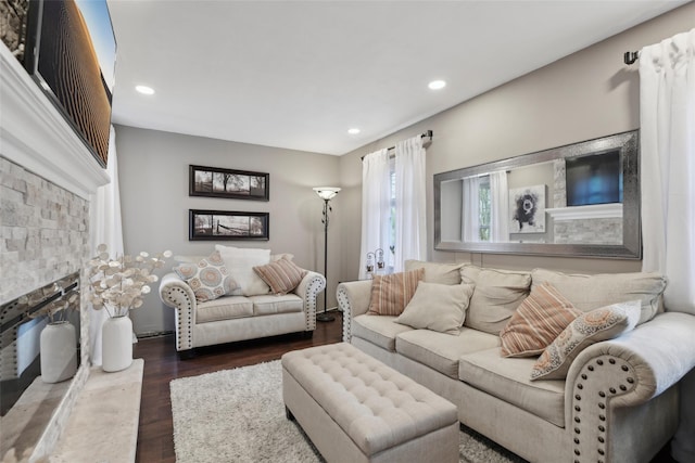 living area with wood finished floors, recessed lighting, and a stone fireplace