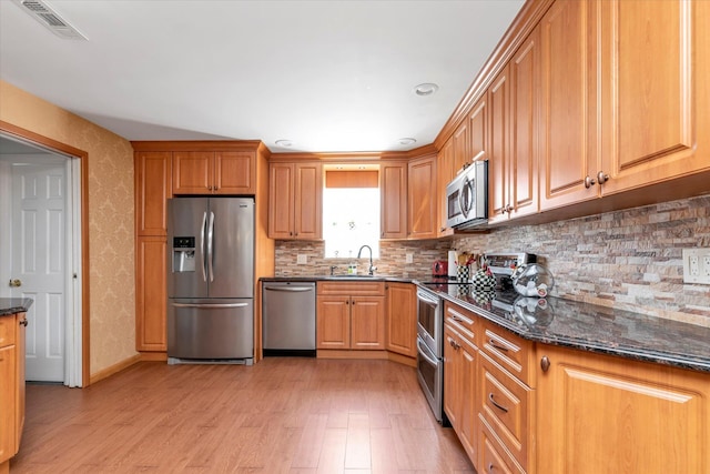 427 Wanamaker St, Oceanside, NY 11572 - kitchen with decorative backsplash, light wood-style floors, dark stone countertops, visible vents, and appliances with stainless steel finishes