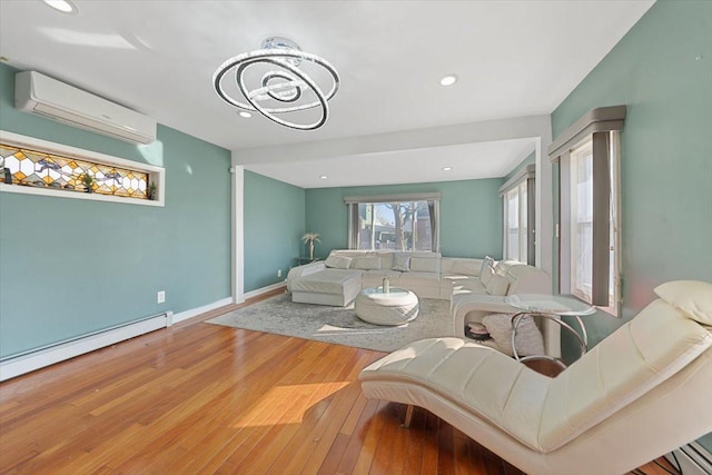 living area featuring a baseboard heating unit, baseboards, a notable chandelier, a wall mounted air conditioner, and hardwood / wood-style flooring