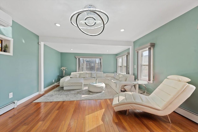 living room with hardwood / wood-style flooring, a baseboard radiator, baseboards, and a wall unit AC