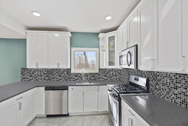 kitchen featuring dark countertops, white cabinetry, stainless steel appliances, and a sink