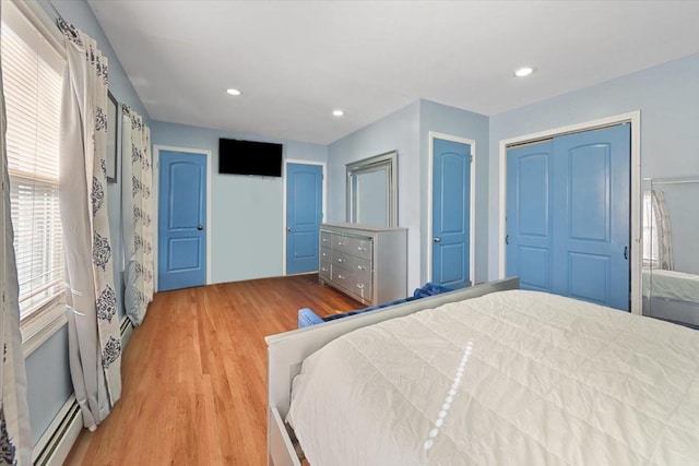 bedroom featuring a baseboard heating unit, recessed lighting, a closet, and light wood-style flooring