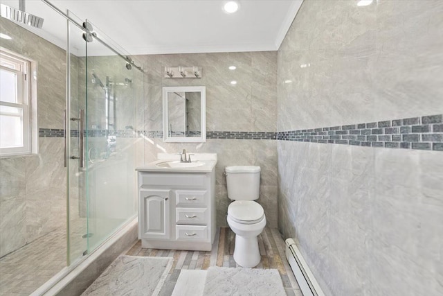 full bath with toilet, tile walls, baseboard heating, a shower stall, and vanity