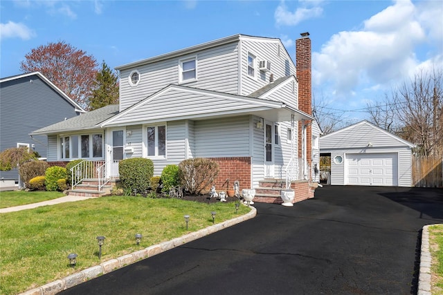 traditional home featuring a chimney, a front yard, a garage, brick siding, and an outdoor structure