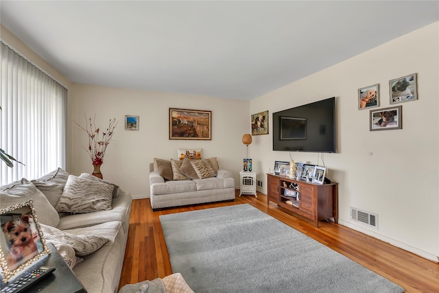living room with visible vents, baseboards, and wood finished floors