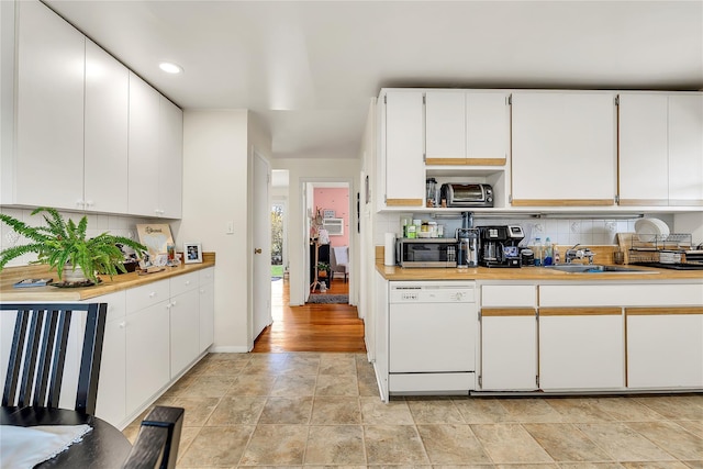 kitchen with white dishwasher, light countertops, backsplash, and a sink