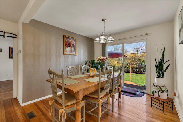 dining room with an inviting chandelier, visible vents, baseboards, light wood-type flooring, and a barn door